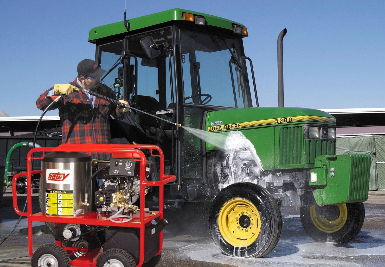 Man power washing a John Deere using a Hotsy Power Washer