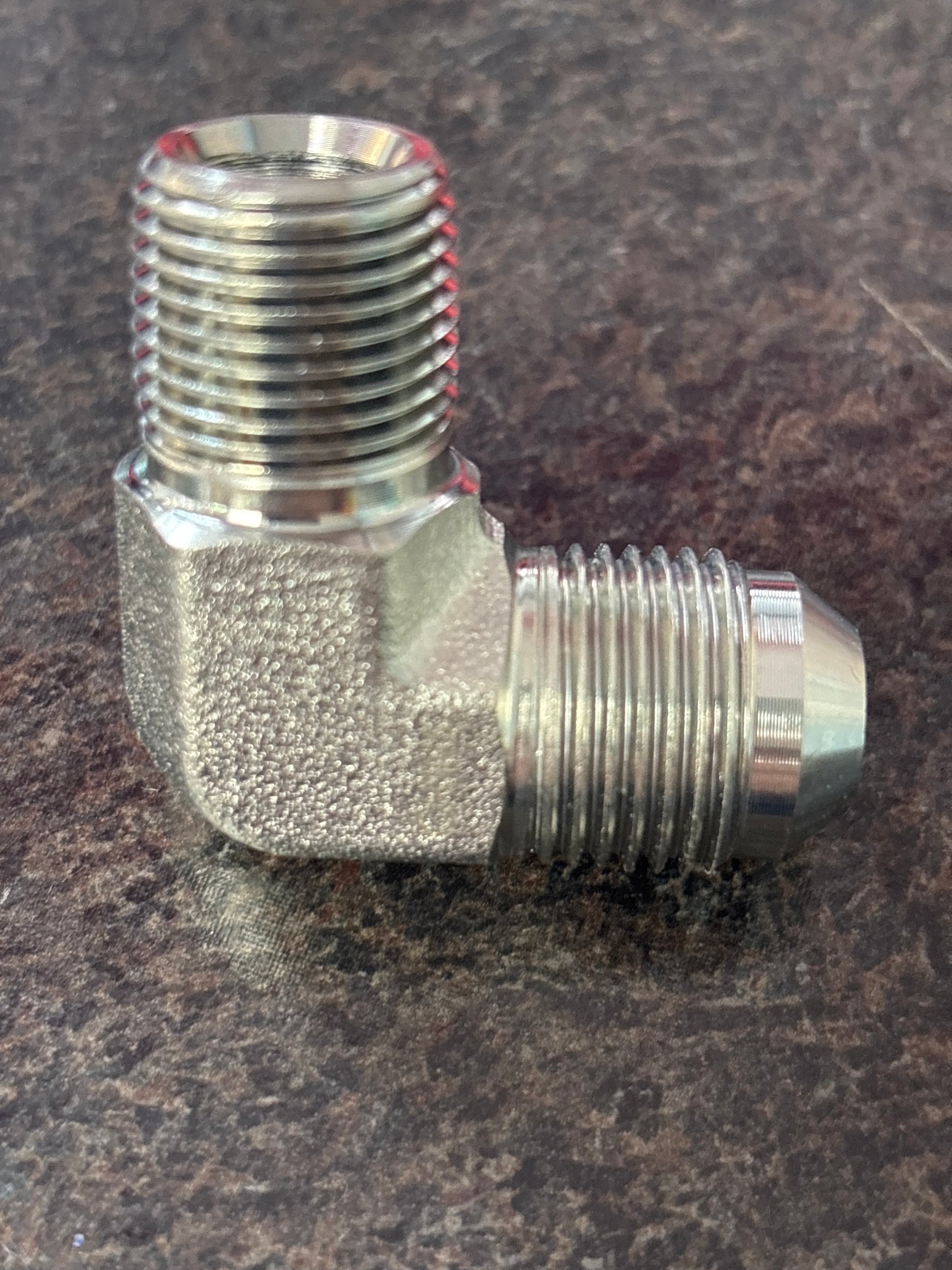 Metal elbow fitting on a brown surface