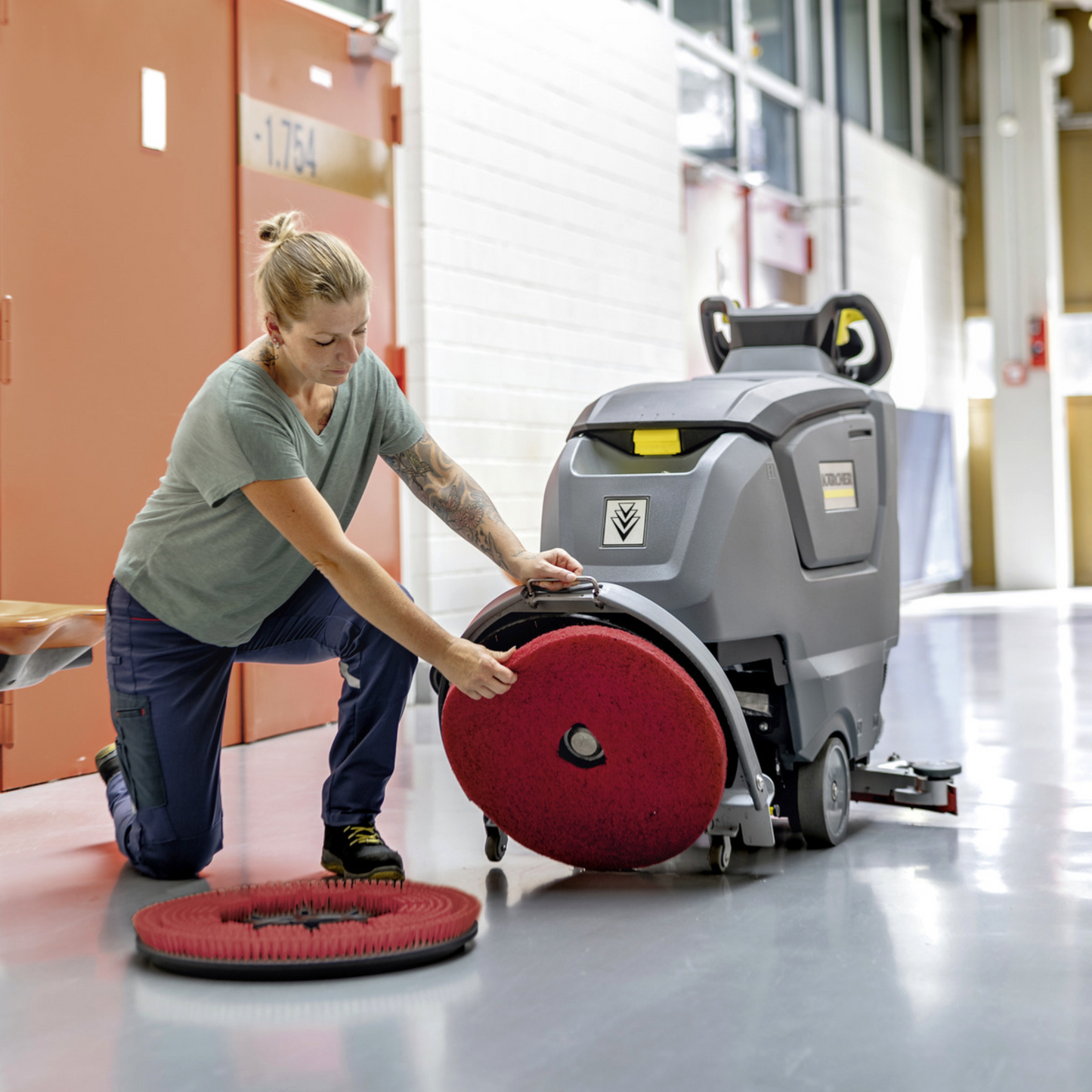 Woman changing a pad for a B 50 W Bp ORB walk-behind floor scrubber