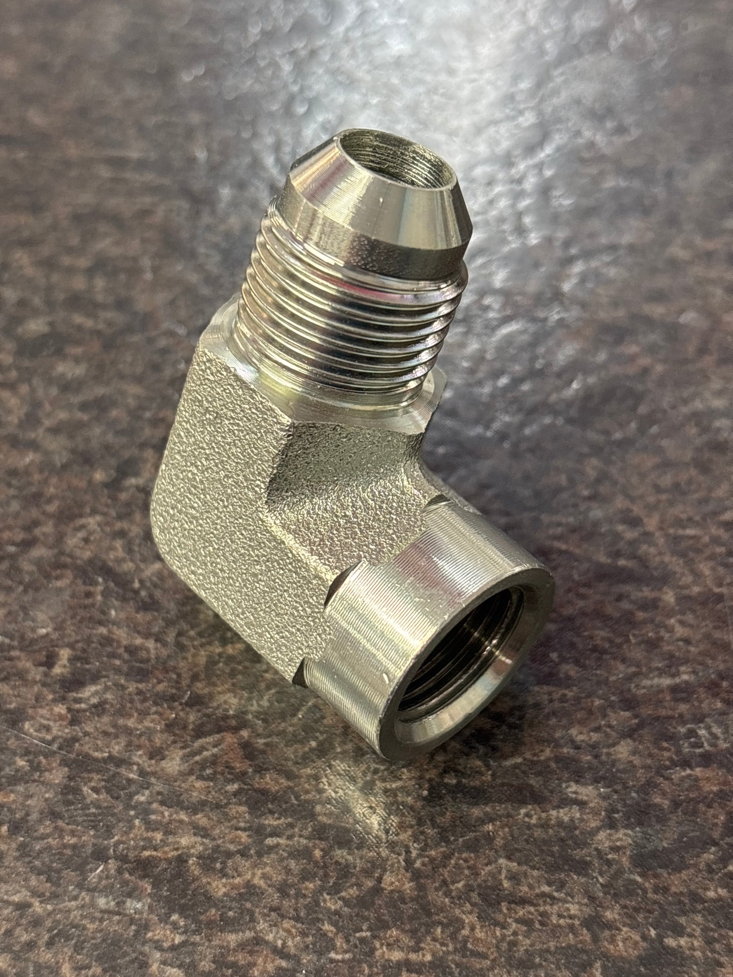 Metal pipe fitting on a textured brown background