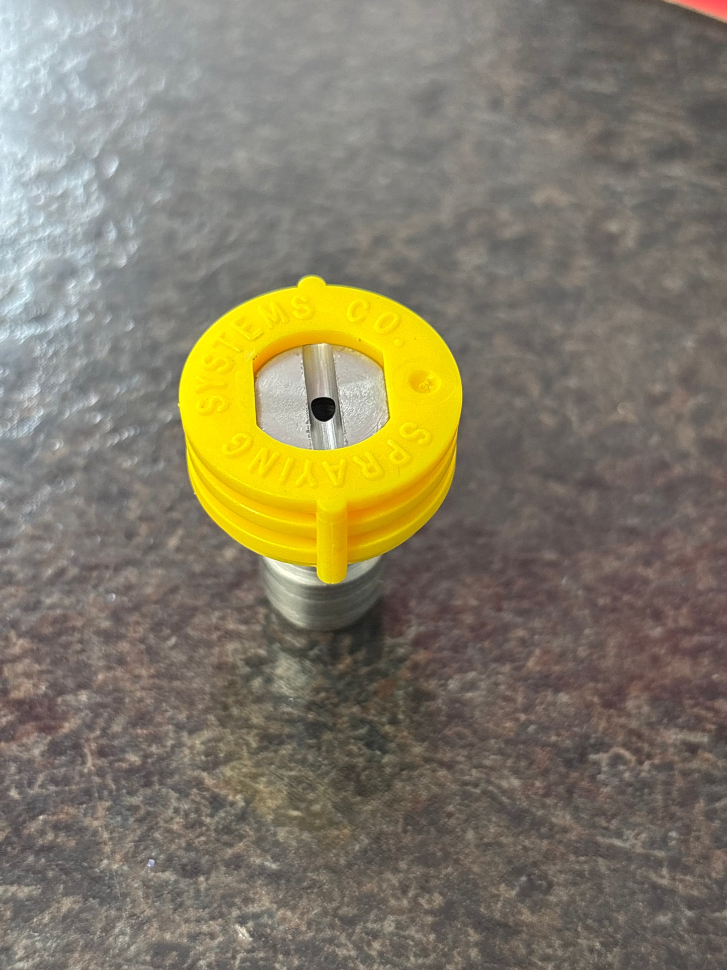 Yellow spray nozzle on a textured gray background