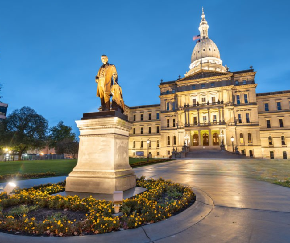 Statue in front of the Michigan State Capitol building at night.