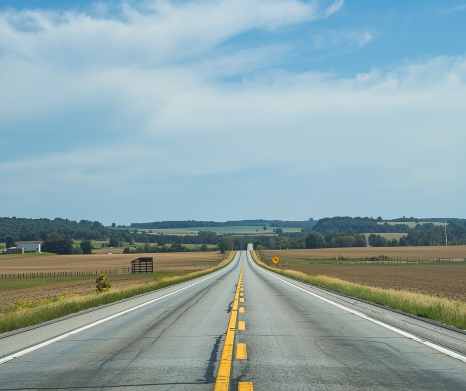Long straight road stretching into the distance with a clear blue sky.
