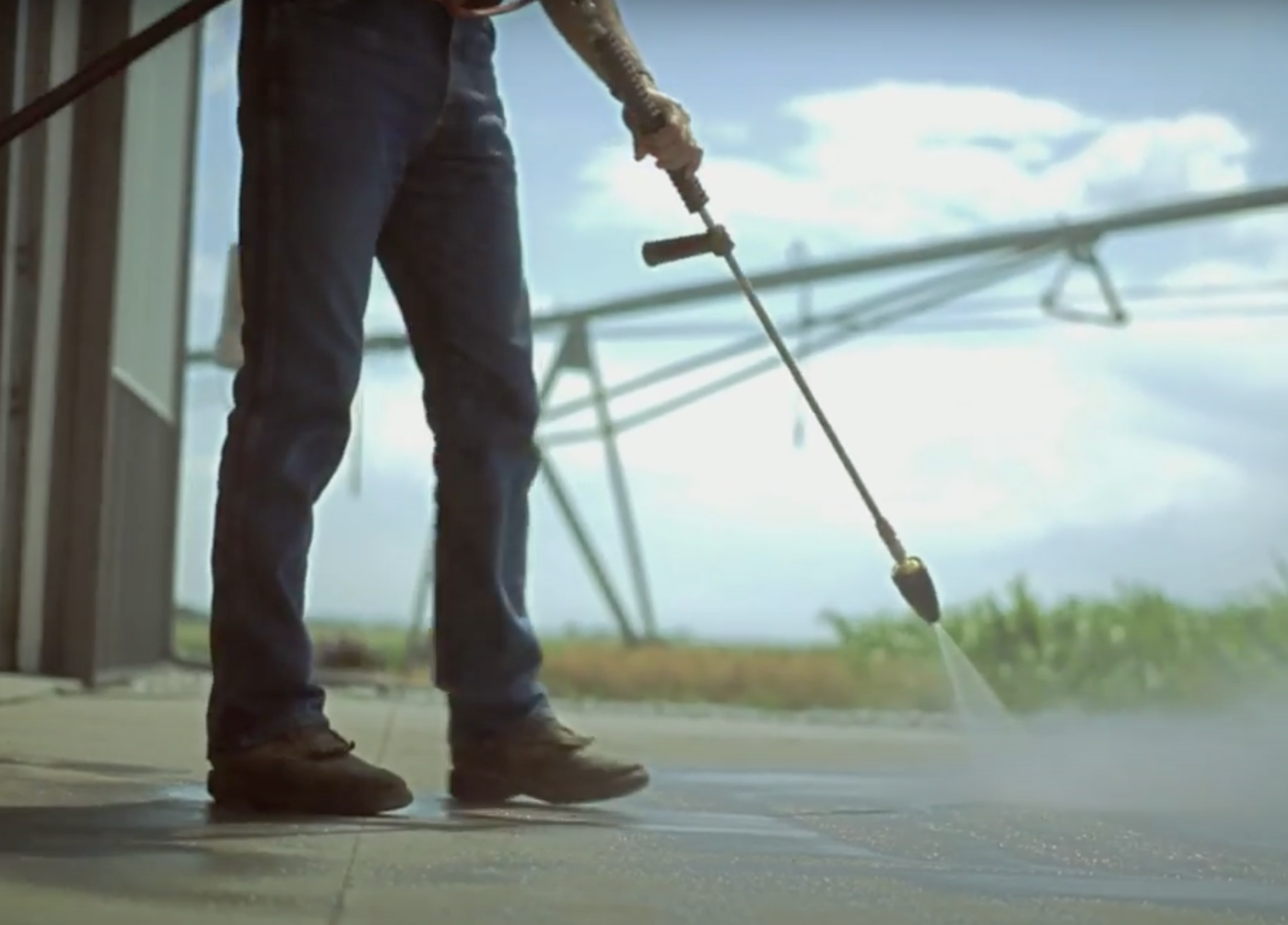 Man in boots pressure washing workshop floor
