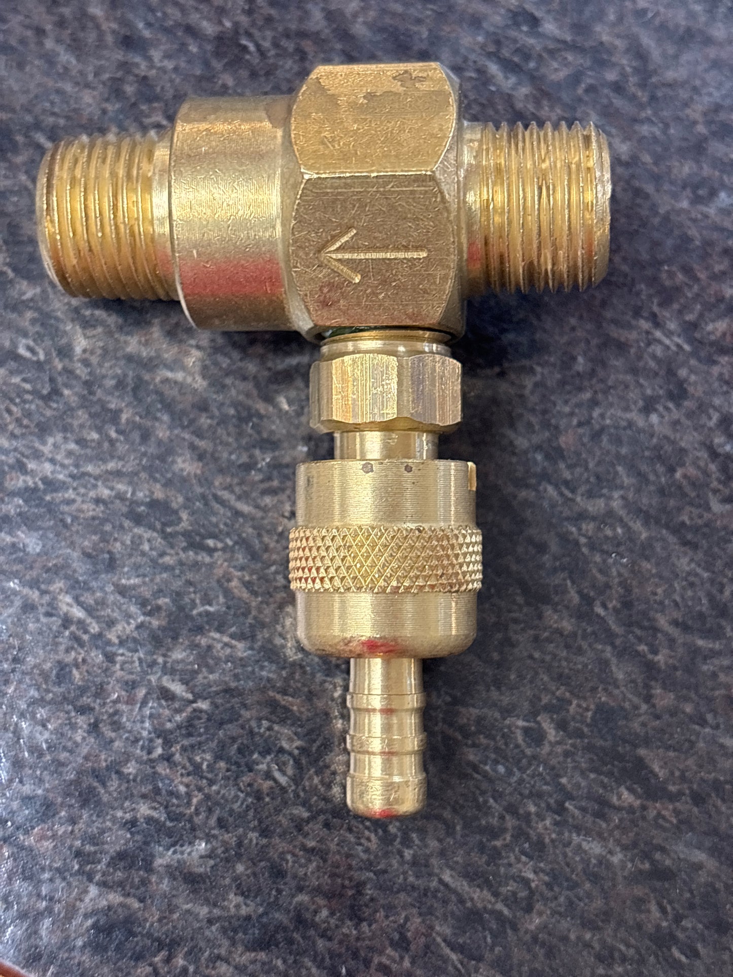 Brass plumbing fitting on a dark textured background