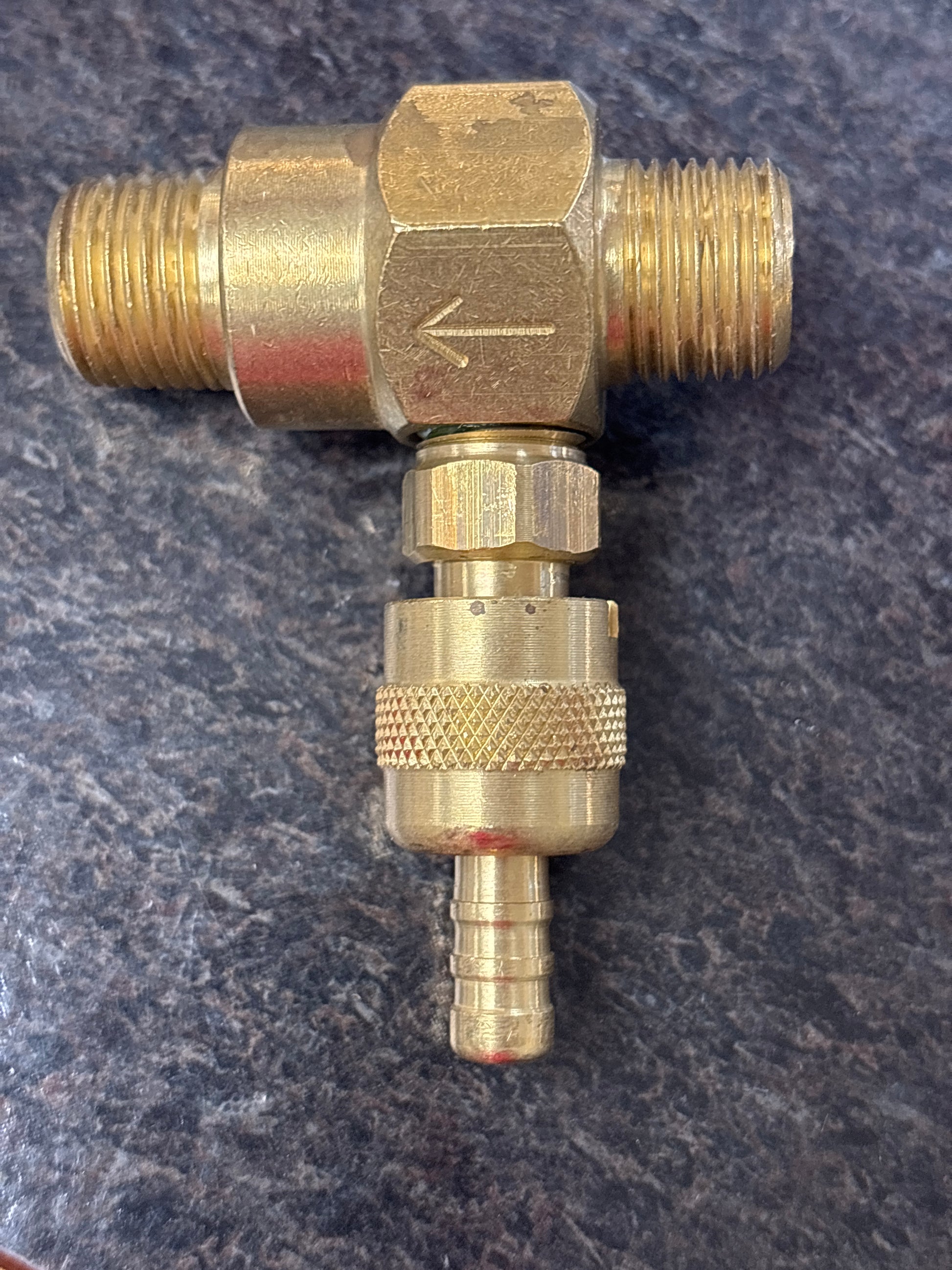 Brass plumbing fitting on a dark textured background