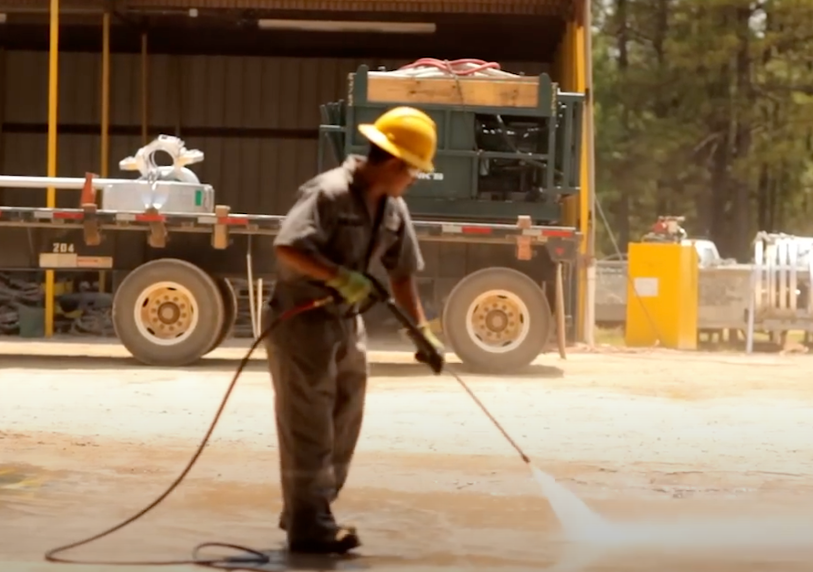 Man in OSHA gear pressure washing a workspace